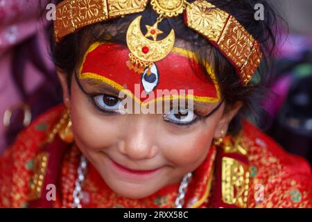 Kumari Pooja au Népal Une jeune fille népalaise pré-pubère pose pour une photo alors qu'elle assiste à la messe Kumari Pooja organisée à Basantapur Durbar Sqaure - un site du patrimoine mondial de l'UNESCO dans la capitale népalaise Katmandou. Vêtues de robes rouges, la déesse vivante Kumari Newa : les filles s'assoient en ligne pour être adorées tour à tour pour conjurer la malchance et les maladies. Les filles pré-pubères sont adorées chaque année inn la nation himalayenne comme incarnations terrestres de l'énergie féminine divine, manifestations de la déesse connue sous le nom Taleju Bhawani, le nom népalais de la déesse Durga. Droit d'auteur : xSubashxShresthax Banque D'Images