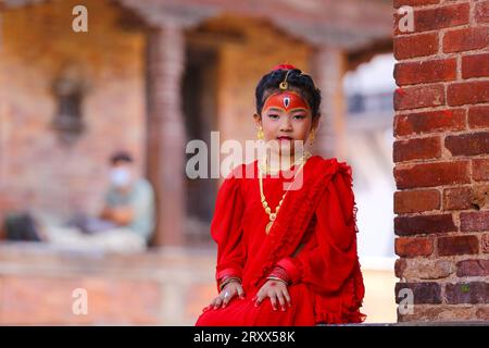 Kumari Pooja au Népal Une jeune fille népalaise pré-pubère pose pour une photo alors qu'elle assiste à la messe Kumari Pooja organisée à Basantapur Durbar Sqaure - un site du patrimoine mondial de l'UNESCO dans la capitale népalaise Katmandou. Vêtues de robes rouges, la déesse vivante Kumari Newa : les filles s'assoient en ligne pour être adorées tour à tour pour conjurer la malchance et les maladies. Les filles pré-pubères sont adorées chaque année inn la nation himalayenne comme incarnations terrestres de l'énergie féminine divine, manifestations de la déesse connue sous le nom Taleju Bhawani, le nom népalais de la déesse Durga. Droit d'auteur : xSubashxShresthax Banque D'Images