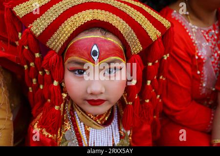 Kumari Pooja au Népal Une jeune fille népalaise pré-pubère pose pour une photo alors qu'elle assiste à la messe Kumari Pooja organisée à Basantapur Durbar Sqaure - un site du patrimoine mondial de l'UNESCO dans la capitale népalaise Katmandou. Vêtues de robes rouges, la déesse vivante Kumari Newa : les filles s'assoient en ligne pour être adorées tour à tour pour conjurer la malchance et les maladies. Les filles pré-pubères sont adorées chaque année inn la nation himalayenne comme incarnations terrestres de l'énergie féminine divine, manifestations de la déesse connue sous le nom Taleju Bhawani, le nom népalais de la déesse Durga. Droit d'auteur : xSubashxShresthax Banque D'Images