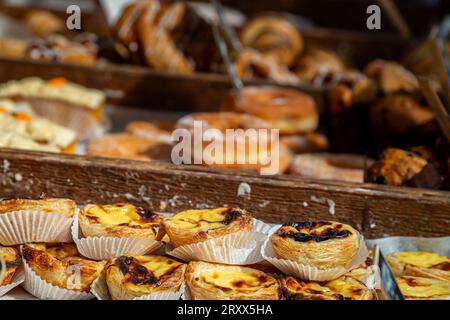 Tartes à la crème anglaise et autres gâteaux et pâtisseries sur un étal de marché, avec une faible profondeur de champ Banque D'Images