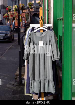 Robes suspendues à un rail devant la boutique de vêtements dans les rues de Manchester, à Ancoats par un après-midi ensoleillé. Banque D'Images