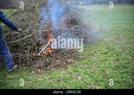 Un jardinier brûle des branches de déchets dans un jardin dans un village traditionnellement Banque D'Images