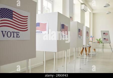 Intérieur d'un bureau de vote vide avec une rangée de bureaux de vote blancs avec des drapeaux américains Banque D'Images