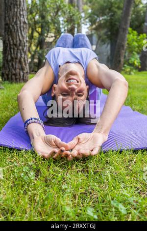 Heureuse femme souriante couchée sur des blocs de yoga en regardant la caméra. Tir vertical Banque D'Images