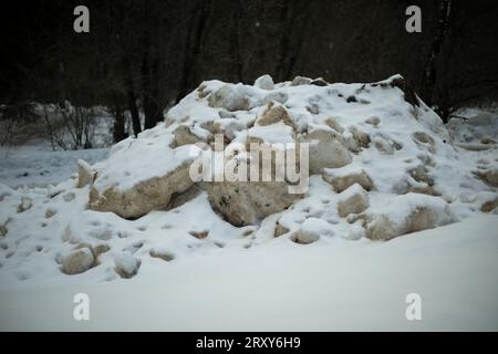 Neige sale par la route. Côté de route en hiver. Les blocs de glace sont noirs. Déneigement. Banque D'Images