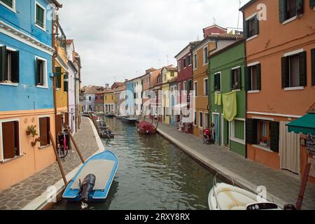 Burano, Vénétie, Italie, septembre 2023, scène de rue montrant des bateaux sur le canal et des maisons peintes colorées Banque D'Images