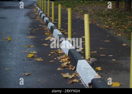 Bornes jaunes le long de la zone piétonne. Restriction du stationnement sur la passerelle. Bordure peinte. Marquages pour le transport. Banque D'Images