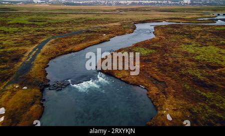 Magnifique panorama de cascade d'oxarafoss, drone shot de cascade islandaise courant vers le bas de la falaise. Énorme ruisseau d'eau coulant et tombant des collines rocheuses massives en islande. Ralenti. Banque D'Images