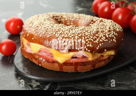 Délicieux bagel avec jambon et fromage sur table en marbre foncé, gros plan Banque D'Images