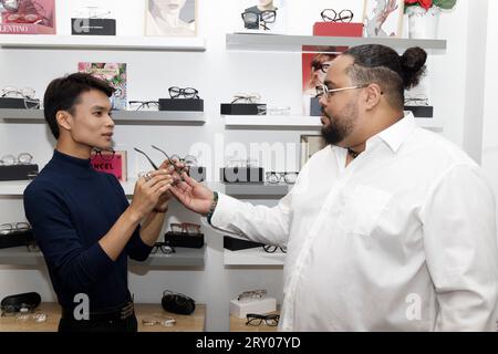 Paris, France. 27 septembre 2023. Le modèle Jeremy Bellet est conseillé sur son choix de lunettes par Alexandre Fontaine propriétaire du 'Watch Out! Boutique la lunette autrement, le 27 septembre 2023 à Paris, France. Crédit : Bernard Menigault/Alamy Live News Banque D'Images