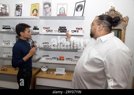 Paris, France. 27 septembre 2023. Le modèle Jeremy Bellet est conseillé sur son choix de lunettes par Alexandre Fontaine propriétaire du 'Watch Out! Boutique la lunette autrement, le 27 septembre 2023 à Paris, France. Crédit : Bernard Menigault/Alamy Live News Banque D'Images