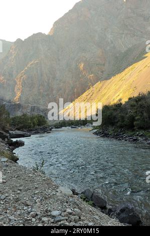 Une petite rivière orageuse dans les rayons des montagnes du soleil couchant coule le long du fond d'un canyon profond par une chaude soirée d'automne. Chulyshman rive Banque D'Images