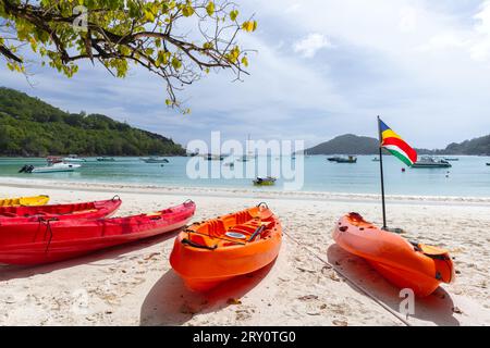 Paysage de plage avec kayaks en plastique rouge et drapeau des Seychelles par une journée ensoleillée Banque D'Images