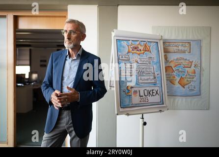 27 septembre 2023, Saxe, Dresde : Armin Schuster (CDU), ministre de l'intérieur de Saxe, se tient à côté d'une représentation visuelle de l'exercice interdépartemental de gestion de crise de LÜKEX au ministère de l'intérieur. Le scénario de l'exercice LÜKEX envisage des attaques contre l'action du gouvernement. Photo : Robert Michael/dpa Banque D'Images