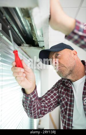 homme utilisant un tournevis sur une fenêtre Banque D'Images