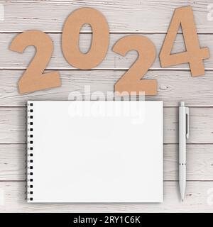 Numéros de papier cartonné 2024 Happy New Year Sign Near White Spiral Paper Cover Notebook avec stylo sur fond de table en bois. Rendu 3D. Banque D'Images
