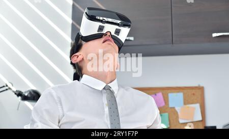 Jeune Trader Homme regardant vers le haut dans le bureau avec des lunettes VR. Réalité virtuelle et concept technologique Banque D'Images