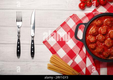 Boulettes de viande à la sauce tomate avec des épices dans une poêle sur une planche de bois blanche. Vue de dessus. Banque D'Images