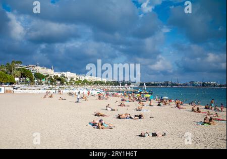 Les gens se détendent sur la plage publique de Mace (Plage Macé) en fin d'après-midi à Cannes sur la Côte d'Azur dans le sud de la France. L'emblématique Carlton Ho Banque D'Images