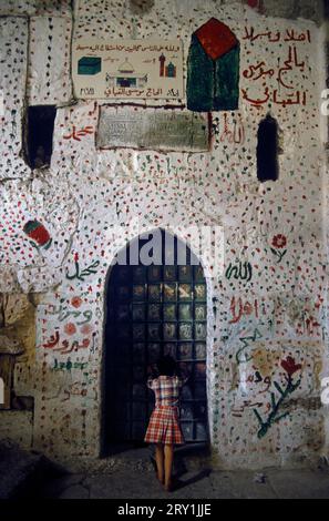 Jérusalem 1980s. Une maison palestinienne dans la vieille ville de Jérusalem, décorée de peinture du Hajj - marques indiquant que les habitants musulmans ont fait un pèlerinage ; le Hajj est un pèlerinage islamique annuel à la Mecque, en Arabie Saoudite, la ville la plus sainte pour les musulmans. La maison est peinte avec des "taches" rouges et vertes deux des couleurs du drapeau palestinien, les autres couleurs étant blanc et noir. Les centres de dessin à gauche sont la Kaaba (Cube) à la Mecque et la mosquée Al Aqsa (Dôme du Rocher) à Jérusalem et peut-être la mosquée Ibrahimi à Hébron. Jérusalem, Israël avril 1982. HOMER SYKES Banque D'Images