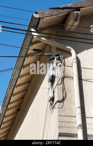 Boîtiers de câblage et de commande pour le téléphone, les données et l'électricité ouverts et visibles le long d'un tuyau d'évacuation contre un mur plâtré d'une maison en France Banque D'Images