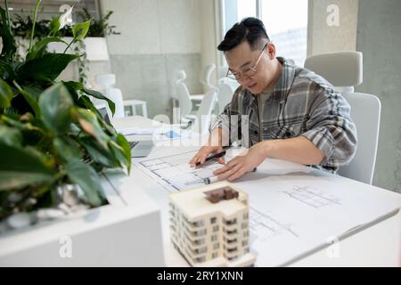Homme architecte travaillant avec des plans modélisant la maison moderne. Banque D'Images
