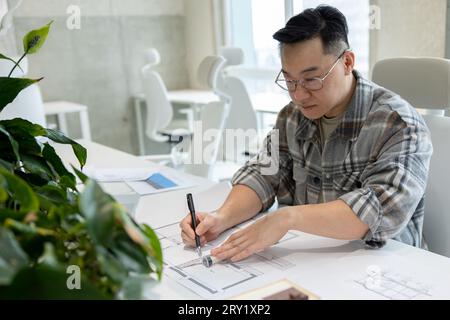 Homme architecte travaillant avec des plans modélisant la maison moderne. Banque D'Images