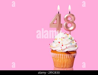 Gâteau d'anniversaire avec bougie numéro 48 - sur fond rose. Banque D'Images