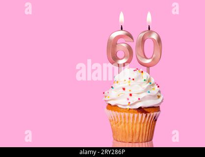 Gâteau d'anniversaire avec bougie numéro 60 - sur fond rose. Banque D'Images