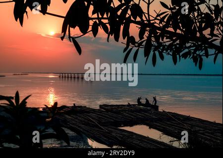 Coucher de soleil sur la rivière. Pêcheurs au coucher du soleil, rivière Brahmapoutre. Dibrugarh, Assam, Inde. Banque D'Images