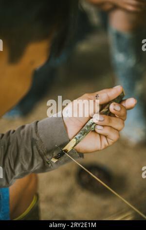 D'en haut de l'homme flou de la tribu Huaorani trempant la fléchette dans le poison curare faisant l'arme traditionnelle pour la chasse Banque D'Images