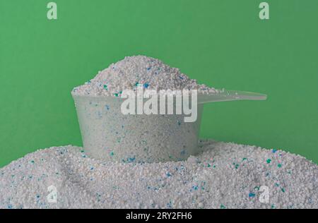 Poudre à laver dans une cuillère en plastique sur un fond vert. Photo de haute qualité Banque D'Images