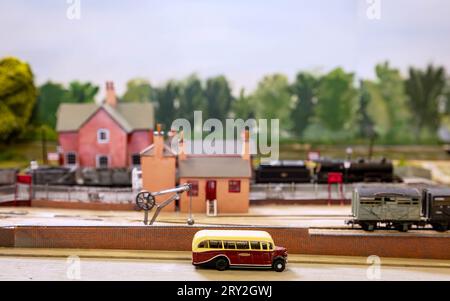 Un autocar des chemins de fer britanniques moulé se trouve au premier plan d'une maquette de l'ancienne gare de Thelwall avec un train à vapeur passant à travers Banque D'Images