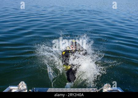 28 septembre 2023, Saxe-Anhalt, Arendsee : un plongeur saute d'un bateau dans l'Arendsee. Là, des archéologues de l'Office d'État de Saxe-Anhalt pour la préservation des monuments et l'archéologie étudient les sites au fond du plan d'eau depuis le 25 septembre 2023. Au total, 20 cibles seront étudiées en haute résolution et en 3D d’ici la fin de la semaine. Entre autres choses, des clôtures à poissons de différentes époques ont été découvertes. L'Institut Fraunhofer d'optronique, d'ingénierie des systèmes et d'exploitation d'images du département d'ingénierie des systèmes appliqués à Ilmenau, la voiture Banque D'Images