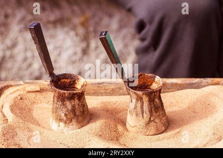 Café turc traditionnel préparé sur sable chaud.. Deux cezves remplis de café oriental chaud. Deux pots pour la préparation du café. jezveh. jezve. Banque D'Images