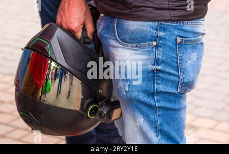 L'homme tient un casque de moto en main. Gros plan photo d'un homme motard brutal garder casque de moto noir Banque D'Images