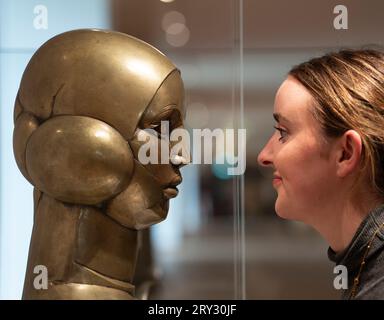 Édimbourg, Écosse, Royaume-Uni. 28 septembre 2023. La nouvelle aile de la National Gallery of Scotland, est officiellement inaugurée aujourd'hui par Angus Robertson MSP accompagné du directeur général des Scottish National Galleries Sir John Leighton. La nouvelle extension ouvre après plusieurs années de construction problématique et de dépassements de coûts. La galerie présente l'art écossais du milieu du 19e siècle au 20e siècle. Pic ; le conservateur de la galerie examine la sculpture moderniste en laiton Eastre (hymne au soleil) de John Duncan Fergusson. Iain Masterton/Alamy Live News Banque D'Images