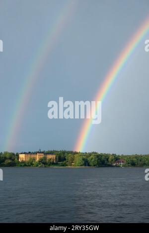 Double arc-en-ciel sur l'eau par le bâtiment de l'école Manilla près de la forêt verte sur Djurgården à Stockholm Banque D'Images