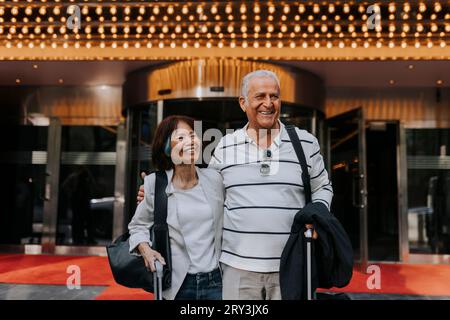 Heureux amis seniors masculins et féminins debout devant le cinéma Banque D'Images