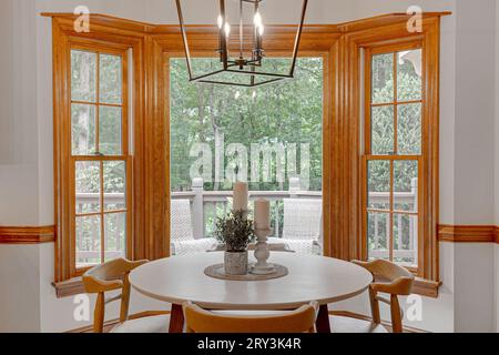 Vue sur la nature depuis l'espace petit déjeuner intérieur de la cuisine avec table ronde moderne et chaises en bois Banque D'Images