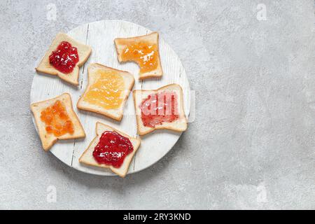 Assiette de délicieux toasts avec différents confitures sur fond gris grunge Banque D'Images
