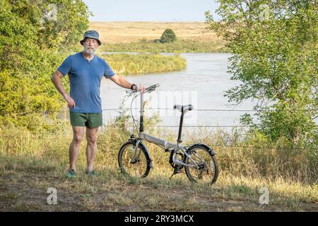 Homme âgé athlétique avec un vélo pliant sur une rive de la rivière Dismal dans Whitetail Campground dans la forêt nationale du Nebraska Banque D'Images