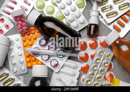 Différentes pilules, seringue et bouteilles de médicaments sur fond gris Banque D'Images