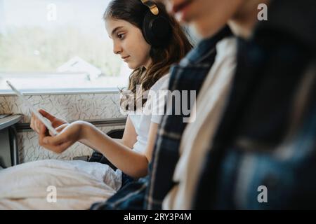 Fille portant un casque bluetooth tout en regardant Tablet PC dans le train Banque D'Images