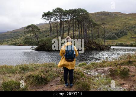 Eine Touristin und Harry Potter Fan besucht die einmalige Filmkulisse - Die Insel Eilean na moine im Süßwasser See Loch Eilt in den schottischen Highlands dient in den Harry Potter Filmen als Filmkulisse als Grabstätte von Professor Albus Dumbledore. Seitdem wird dieser einsame Ort an dem zudem die West-Highland-Eisenbahnstrecke mit dem dampfbetriebenen Jacobite train à vapeur Poudwarts Express vorbei führt, von vielen fans und Touristen aufgesucht. 22.09.2023 Loch Eilt Schottland Großbritannien *** Un touriste et fan de Harry Potter visite le décor unique du film l'île d'Eilean na moine dans le fres Banque D'Images