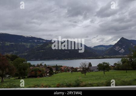 Vue sur la montagne et le village avec ciel nuageux, Berne, Suisse.. Image capturée lors d'un Road trip. Point de vue du passager. Banque D'Images