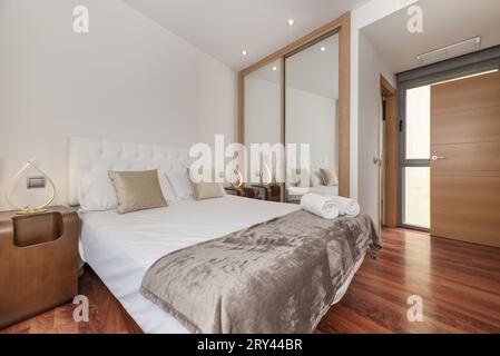 Une chambre double avec une armoire à portes coulissantes avec miroirs, boiseries en chêne et coussins dorés Banque D'Images