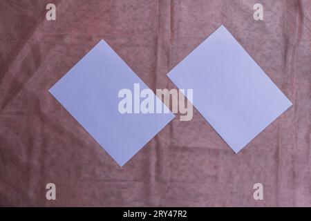 Deux feuilles fuchsia format A4 sur un subtil tissu rose foncé Banque D'Images