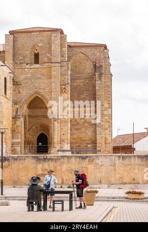 Pèlerins marchant le chemin de pèlerinage Camino de Santiago, le chemin de Saint Jacques, dans la ville espagnole de Villalcazar devant l'église de Santa Maria Banque D'Images