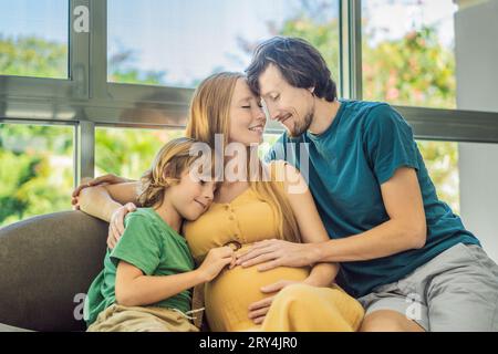 Les futurs parents, maman, papa et leur fils aîné partagent un moment réconfortant sur le canapé, discutant du voyage passionnant de la grossesse Banque D'Images